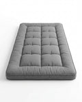 Grey quilted foldable floor comfort mattress, studio shot on white
