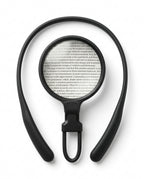 Black hands-free neck magnifier with round lens over a page of text, top-down