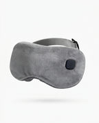 Grey plush heated eye massager mask with power button, studio shot on white