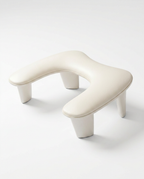 Cream U-shaped padded nail arm rest cushion on four tapered legs