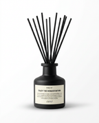 Matte black reed diffuser bottle with black reeds and minimalist label on white
