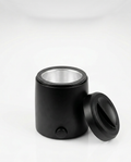 Black home wax warmer with lid off and aluminum well, studio shot on white