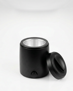 Black home wax warmer with lid off and aluminum well, studio shot on white