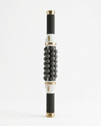 Electric rolling massage stick with black balls and gold caps on white
