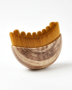 Curved wooden facial comb with soft golden bristles, front view on white