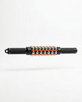Black handheld muscle roller stick with steel balls and orange rails, studio shot