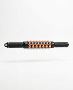 Black handheld muscle roller stick with steel balls and orange rails, studio shot