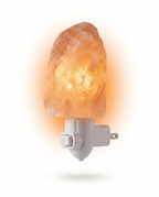Plug-in Himalayan salt lamp glowing warm amber on a white wall base