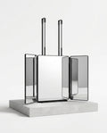 Trifold 360-degree grooming mirror with black frames and straps on stone plinth