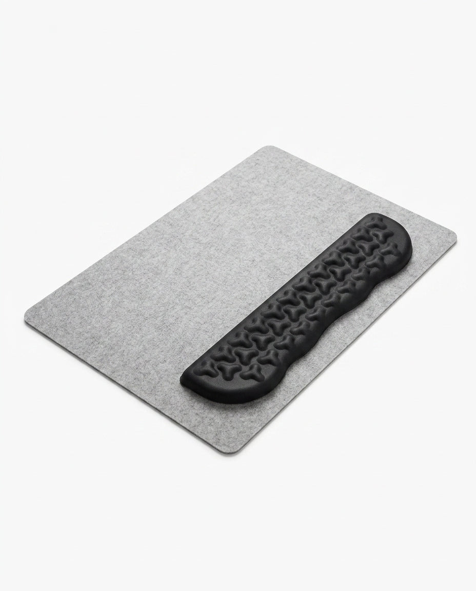 Black contoured memory foam wrist rest on a gray felt desk mat on white