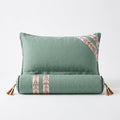 Sage green linen sleep support pillow with bolster, ikat trim and leather tassels, studio shot on white