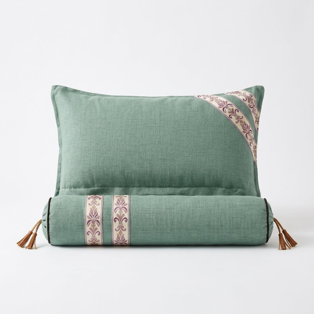 Sage green linen sleep support pillow with bolster, ikat trim and leather tassels, studio shot on white