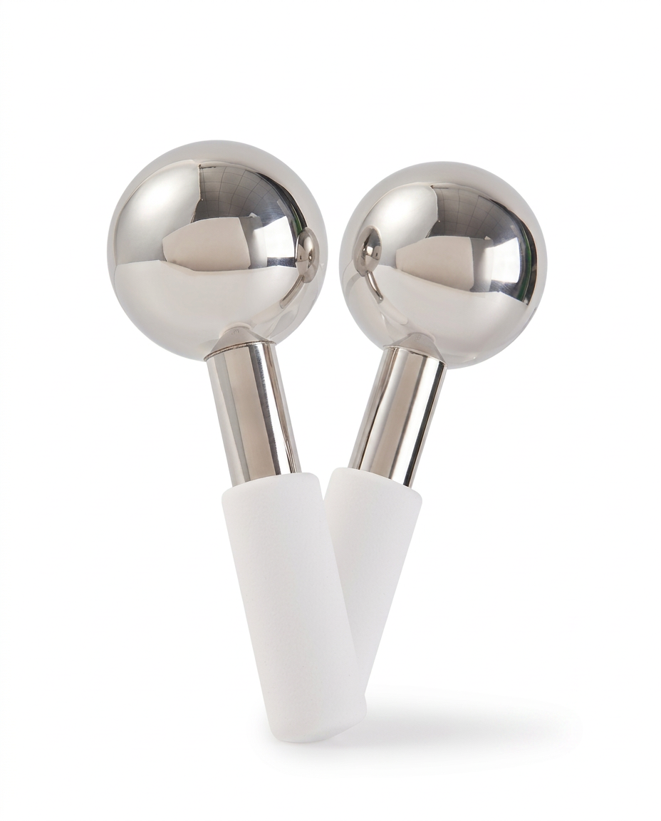 Pair of stainless steel facial ice globes with white handles on white