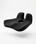 Black contoured memory foam seat cushion with coccyx cutout, floating on white