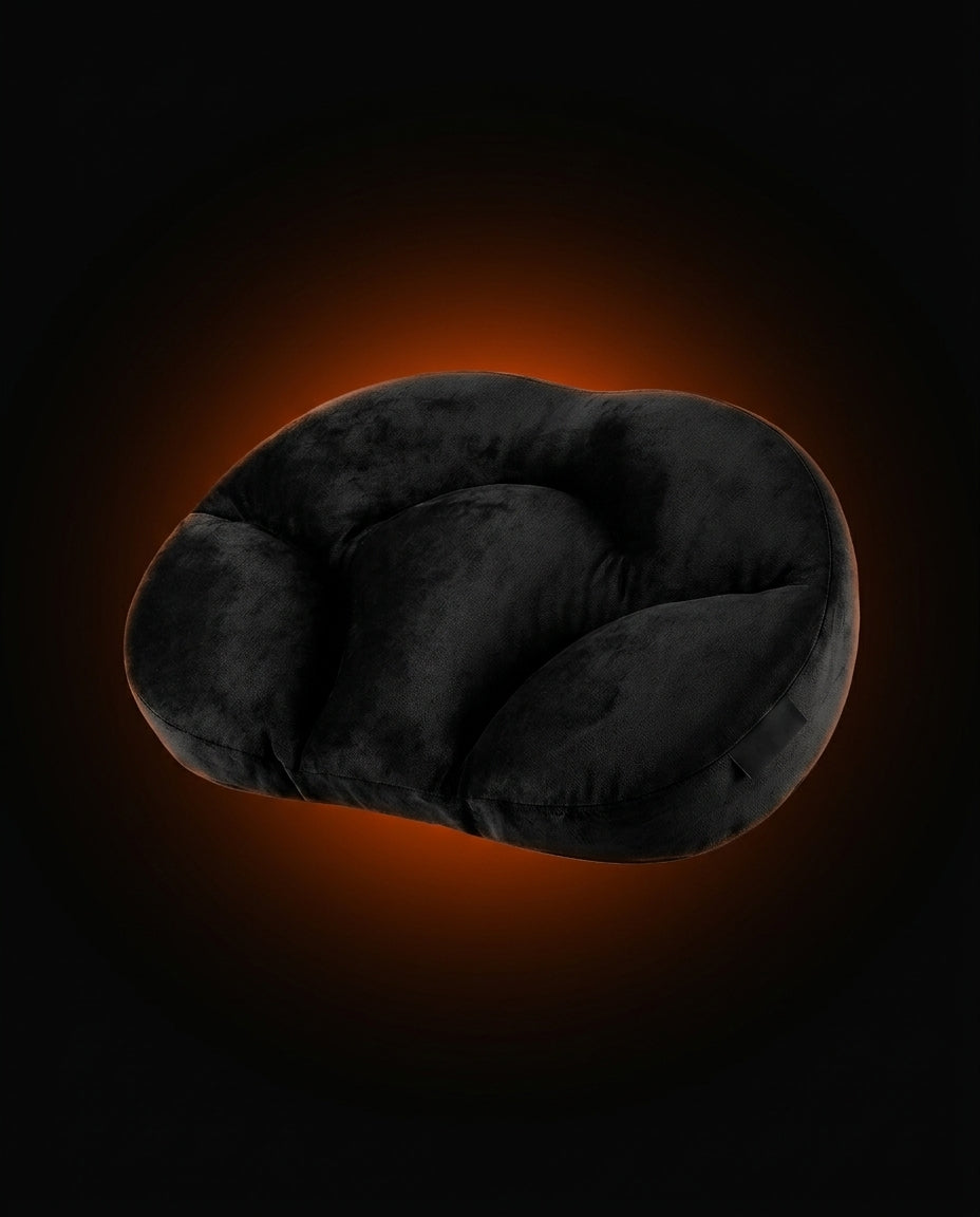 Black contoured neck support pillow on dark background with orange ember glow