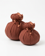 Pair of brown herbal heat massage balls tied with ribbon on white
