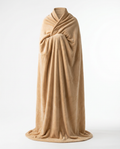 Person fully cocooned in a tan oversized wearable blanket, studio shot