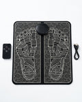Black EMS foot massager mat with reflexology pattern, remote and USB cable on white