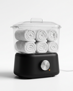 Mini towel warmer holding six rolled white towels under a clear lid