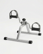 Silver under-desk mini pedal exercise bike with foot straps, studio shot on white