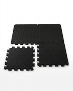 Black EVA foam puzzle exercise mat tiles with interlocking edges on white