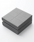 Grey foldable travel yoga mat folded into a compact square, studio shot