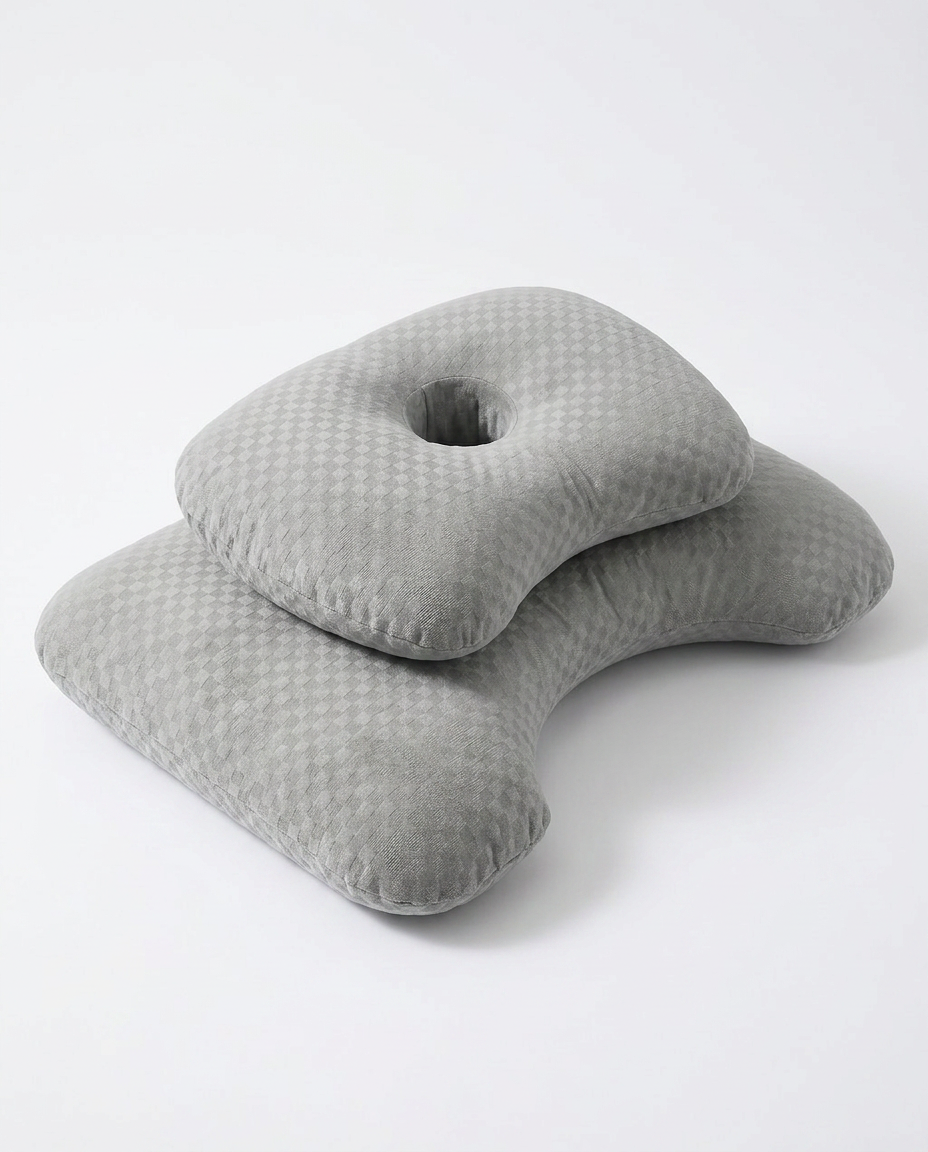 Grey ergonomic side-sleeper pillow with central ear cutout, studio shot on white