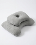 Grey ergonomic side-sleeper pillow with central ear cutout, studio shot on white