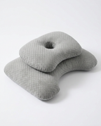 Grey ergonomic side-sleeper pillow with central ear cutout, studio shot on white