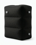 Black inflatable travel footrest pillow with stacked chambers, studio shot on white