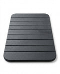 Dark grey grooved diatomite stone bath mat on a white background