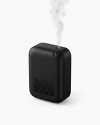 Black smart essential oil diffuser releasing a plume of mist, studio shot
