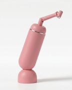 Pink travel bidet bottle standing upright with angled spray nozzle attached