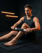 Athlete rolling the massage stick along his calf on a gym mat