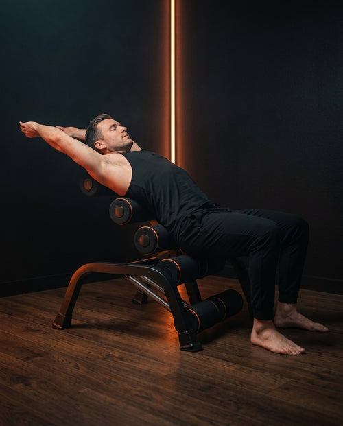 Man doing a back extension stretch on the training bench in a dim room