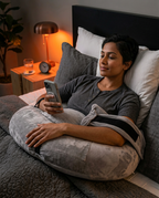 Woman scrolling her phone in bed resting on the hands-free comfort pillow at night
