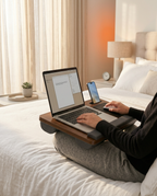 Person typing on a laptop atop the lap desk while sitting in bed