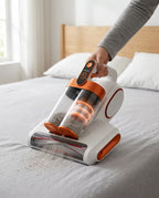 Hand pushing the fabric vacuum across a grey mattress, lifting dust