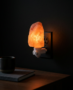 Himalayan salt night light glowing softly beside a dark bedroom nightstand
