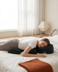 Woman lying prone on a bed, face cradled in the black face-down support pillow