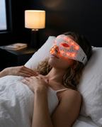 Woman relaxing in bed wearing the glowing red light LED eye mask