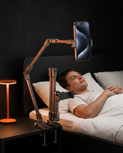 Man in bed at night watching a phone held by the bedside phone arm clamped to a nightstand