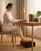 Woman working at a desk with feet on the heated foot cushion in a home office