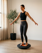 Woman doing a balance workout barefoot on the wobble board at home