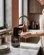 Woman dispensing foam soap touch-free at a marble kitchen counter