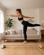 Woman balancing on one leg on the wooden balance beam in her living room