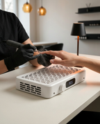 Manicurist filing a client's nail over the dust collector at a salon table