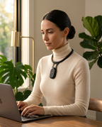Woman at a laptop wearing the posture corrector pendant on her neck