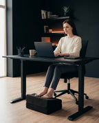 Woman at a desk resting her feet on the black foot rest cushion