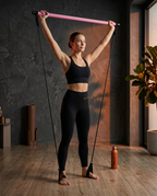 Woman doing an overhead press with a pink Pilates bar at home
